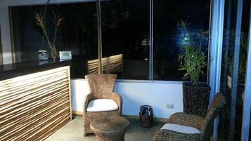 A modern room with wicker furniture, a large window, and a potted plant.