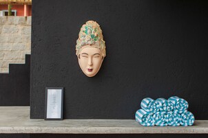 Una escultura de cabeza en una pared, un certificado enmarco y una pila de toallas a rayas.