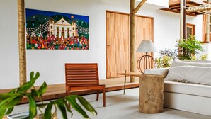 Un soggiorno moderno con una panca di legno, un tavolo rotondo in legno, un divano bianco e un quadro appeso al muro.