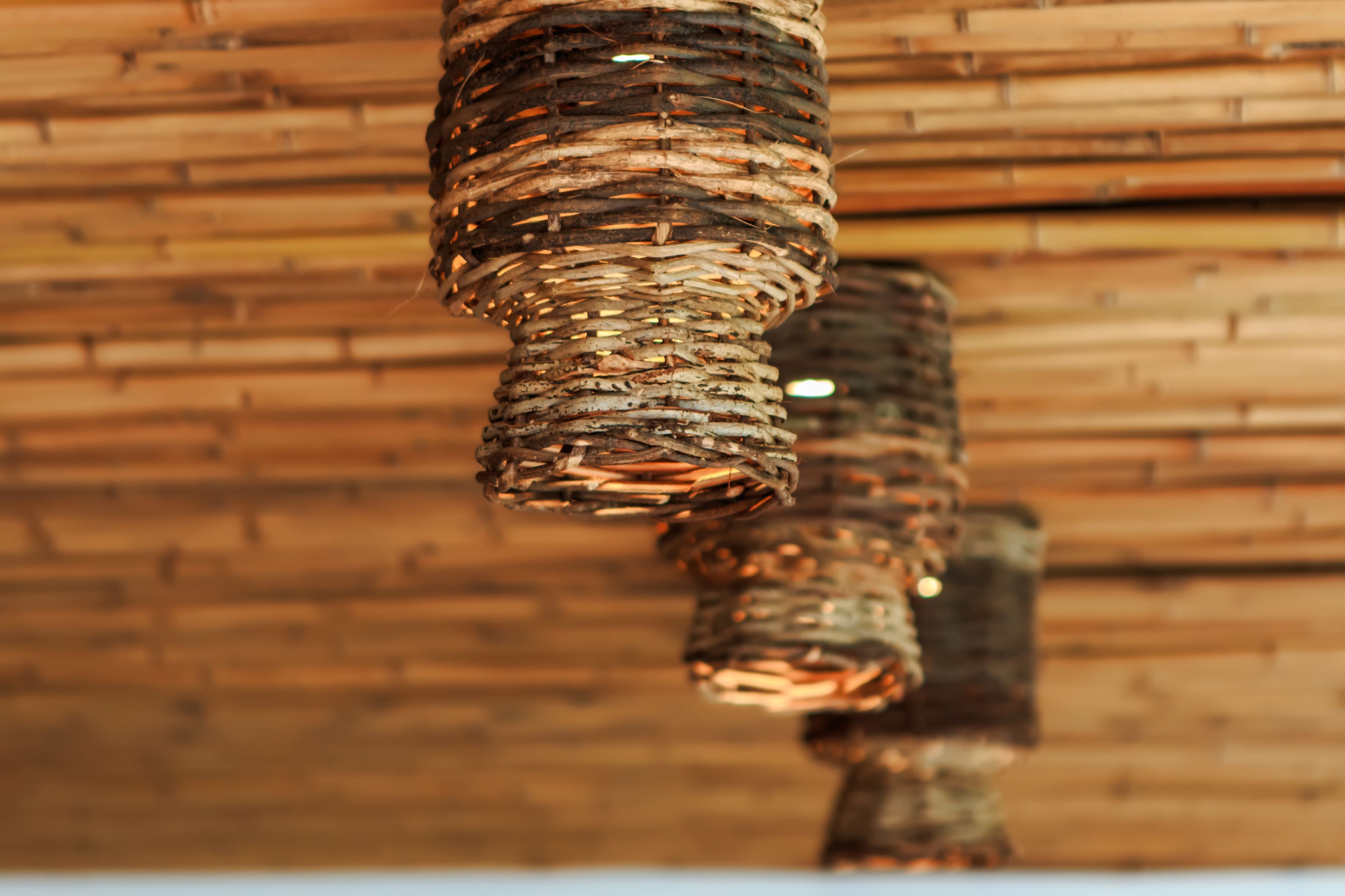 A close-up of a woven, copper-colored structure against a wooden background.