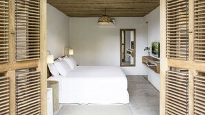 Una camera da letto con un letto, lampade ai comodini, uno specchio e un soffitto in legno.
