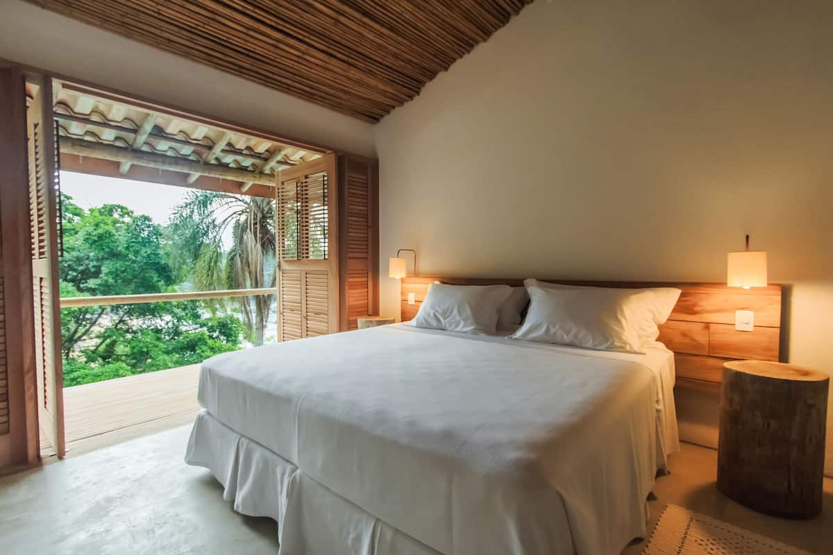 Un dormitorio con una cama grande, cabecera de madera y una mesita de noche con lámpara.