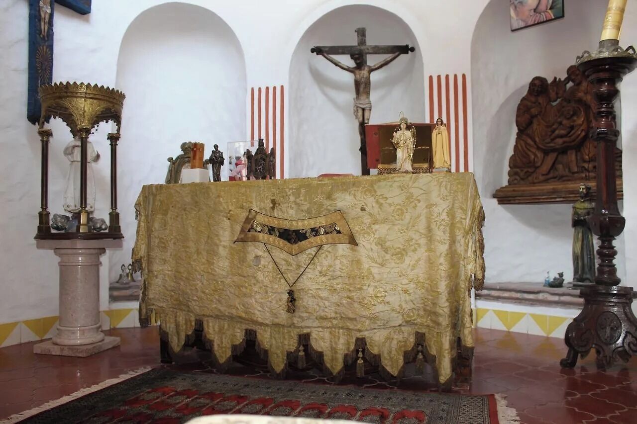 A church interior with a central altar, a crucifix, and religious statues.