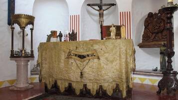 A church interior with a central altar, a crucifix, and religious statues.