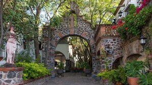 A stone archway leading to a courtyard with potted plants and a statue. - Hotel Ex-Hacienda La Pitaya Queretaro (Apaseo el Grande)