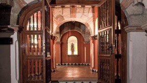 A hallway with wooden doors and a tiled floor leading to a central area with a statue. - Hotel Ex-Hacienda La Pitaya Queretaro (Apaseo el Grande)