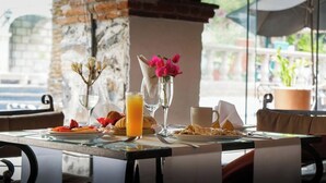 A breakfast table with a glass of orange juice, a vase with pink flowers, and plates of food. - Hotel Ex-Hacienda La Pitaya Queretaro (Apaseo el Grande)