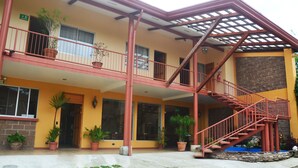 A two-story building with a red staircase and potted plants. - Hotel La Villa (Quesada)