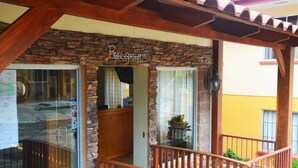 A stone facade with a wooden pergola entrance, a glass door, and a visible sign. - Hotel La Villa (Quesada)