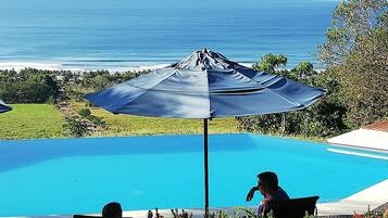 Outdoor pool, an infinity pool, pool umbrellas, sun loungers