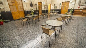 Un espacio interior amplio con varias mesas y sillas, suelo de baldosas y puertas de madera.