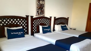 Habitación de hotel con tres camas, cada una con cabecero de madera y ropa de cama azul y blanca.