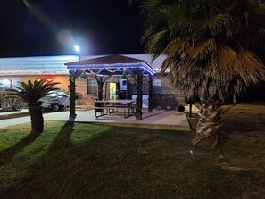 A covered outdoor seating area with a table and chairs, decorated with lights and greenery, in front of a building with a brick facade. - Coldspring Inn (Coldspring)