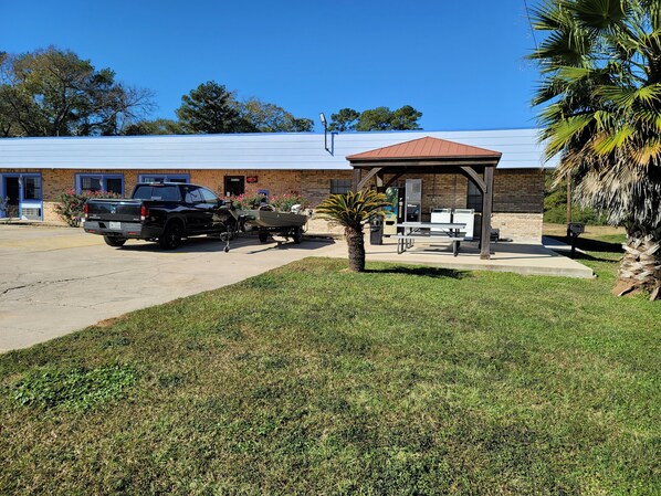 A building with a brick facade, a covered picnic area, and a parked truck. - Coldspring Inn (Coldspring)