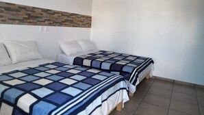 A room with two beds, each with a patterned bedspread. The room has a tiled floor and a wall with a mosaic design. - Hostal Maple (Querétaro)