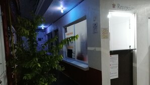 A hallway with a reception desk, a sign for a hostel, and a potted plant. - Hostal Maple (Querétaro)