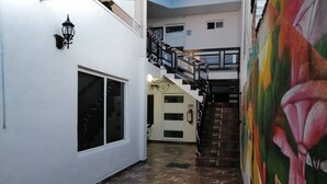 A courtyard with a tiled floor, a staircase, and a mural on the wall. - Hostal Maple (Querétaro)
