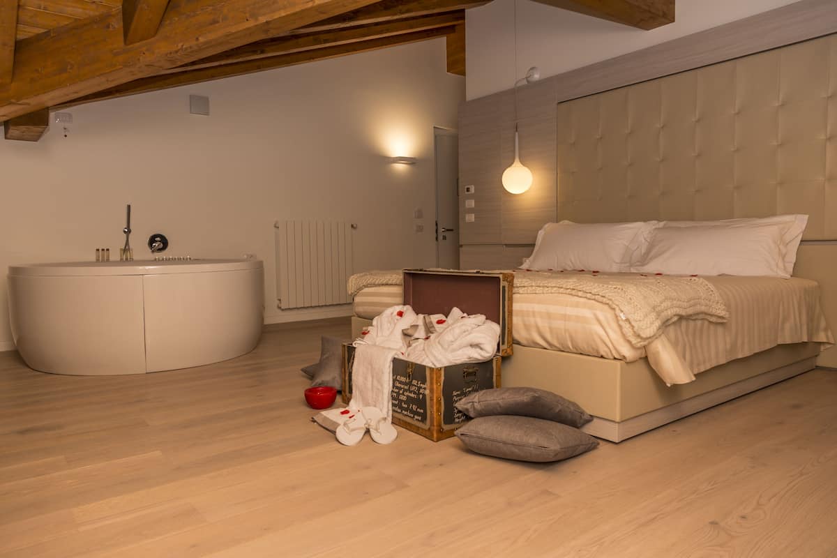 Un dormitorio con cama, maleta, un cuenco rojo y una bañera blanca.