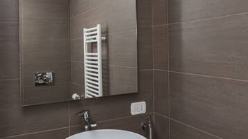Un bagno moderno con un ampio lavandino bianco, uno specchio e un porta asciugamani.