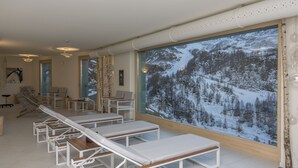 Un cuarto de spa con sillones reclinables, un ventanal con vistas a una montaña nevada y una zona de sauna.