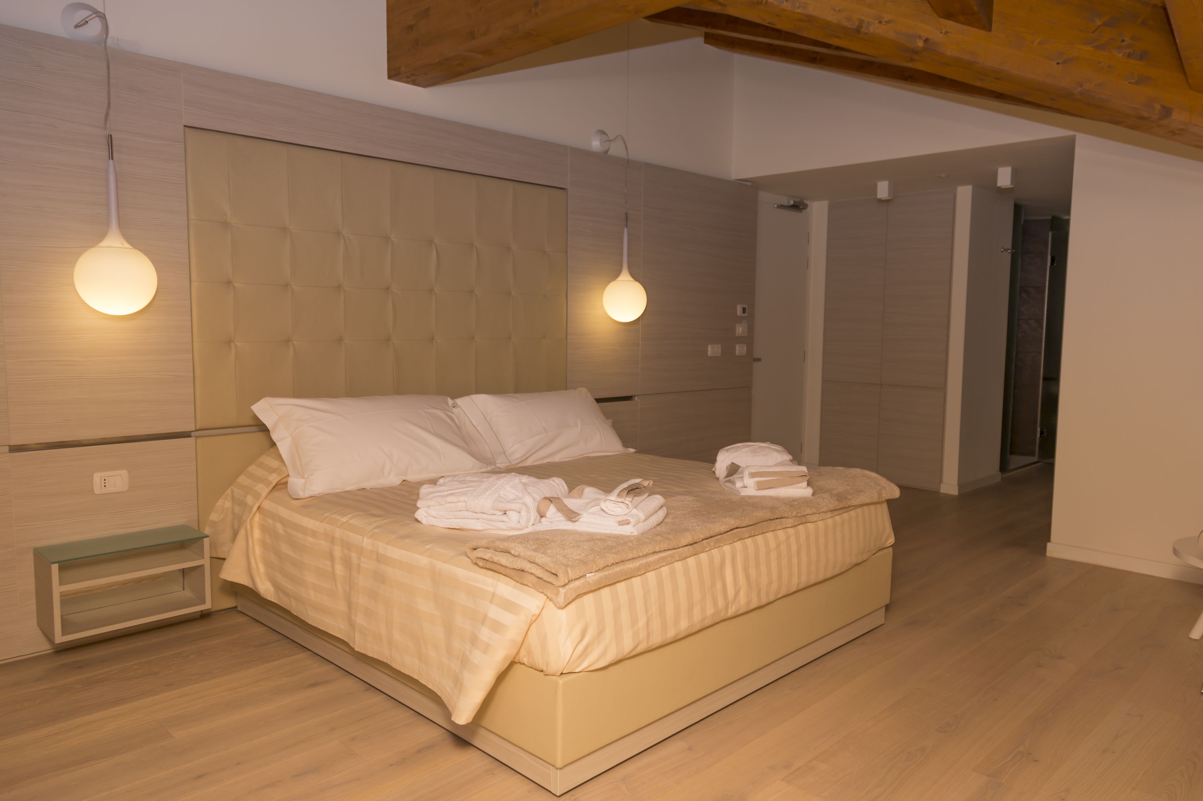 Ein modernes Schlafzimmer mit einem großen Bett, zwei Nachttischlampen und einer Holzbalkendecke.