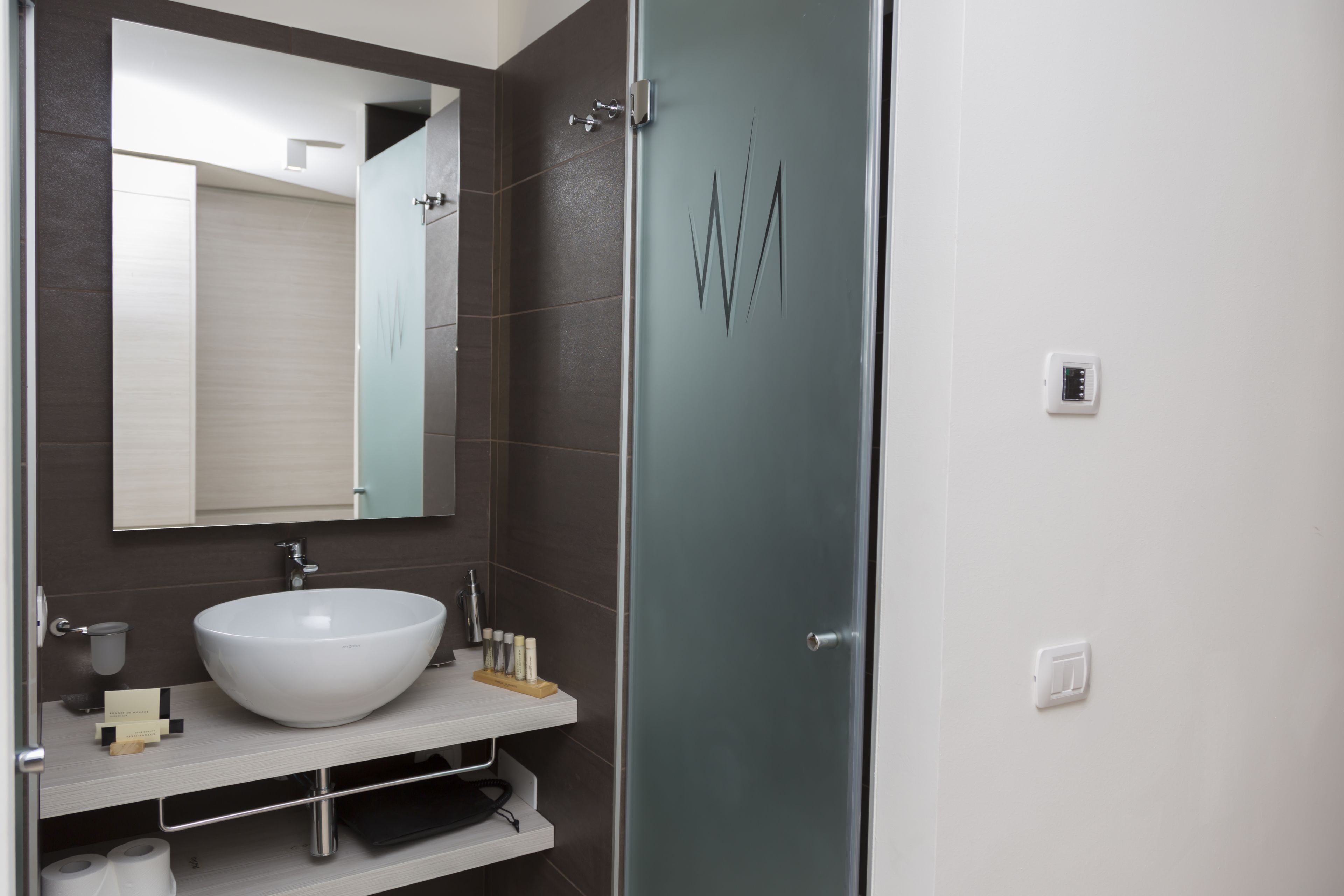 Ein modernes Badezimmer mit einem großen weißen Waschbecken, einem Spiegel und einer Duschkabine aus Glas.