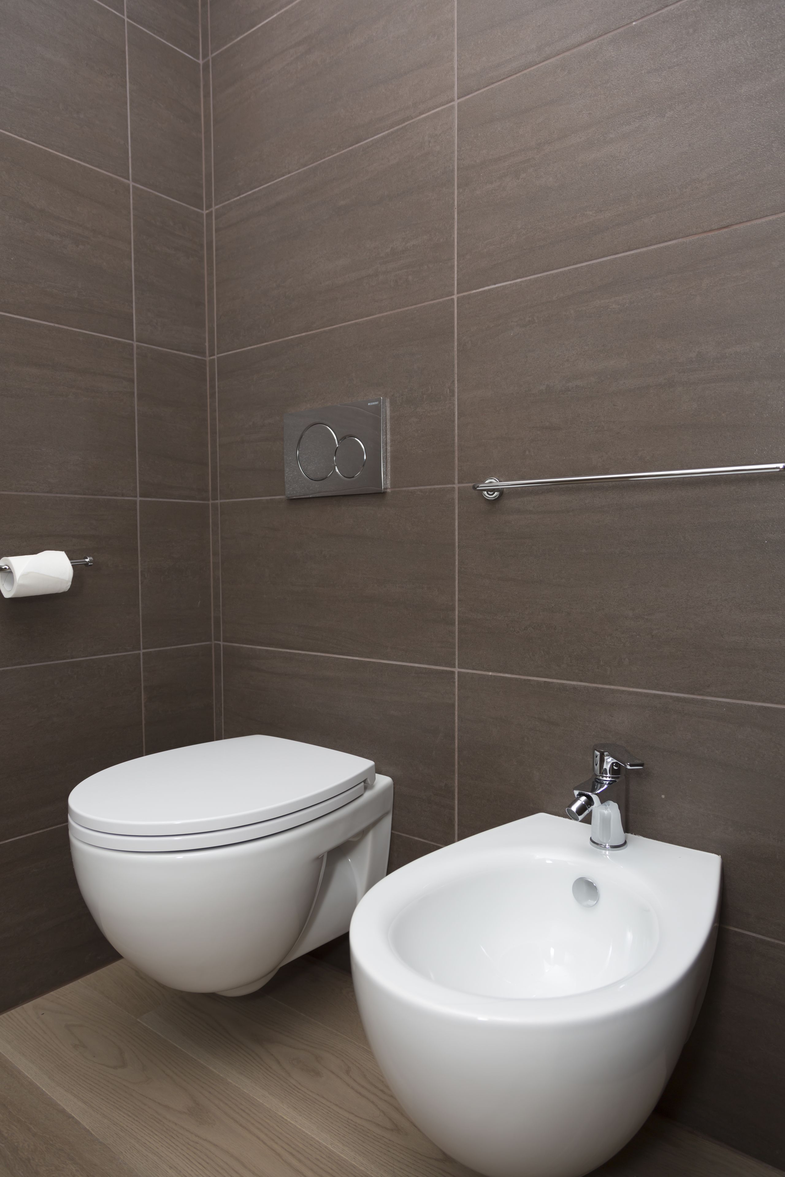Un baño moderno con inodoro, bidé y un perchero para toallas.