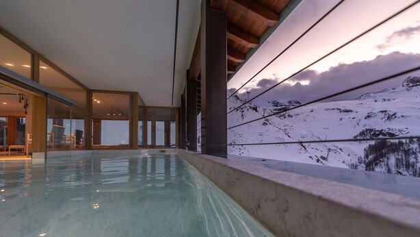 Una piscina interior con vistas a un paisaje montañoso nevado.