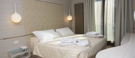 Habitación de hotel moderna con una cama grande, una mesita de noche con teléfono y un estante de vidrio.