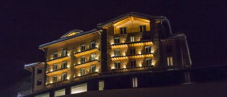 A multi-story hotel with balconies and illuminated windows at night.