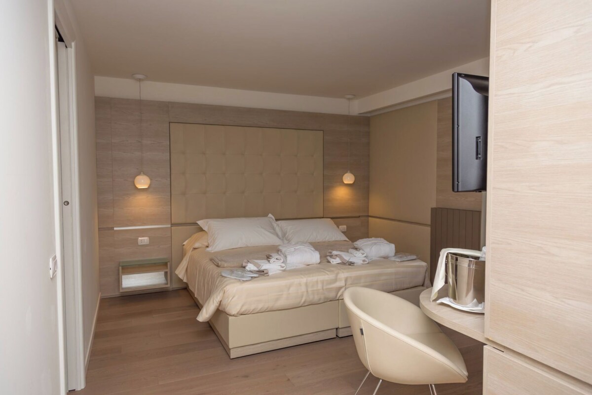 Una habitación de hotel moderna con una cama grande, un escritorio pequeño y una silla.