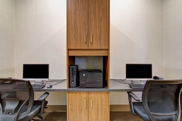 A conference room with two desks, each with a computer and a printer, and two chairs.