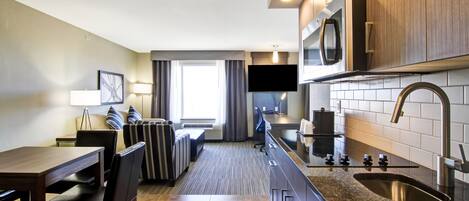 Una habitación de hotel compacta con kitchenette, comedor y zona de estar.