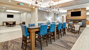 En modern hotellobby med en central bardisk, flera olika sittgrupper och en platt-TV som är monterad på väggen.