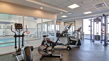 Un gimnasio con bicicletas estáticas, una cinta de correr y máquinas de pesas.