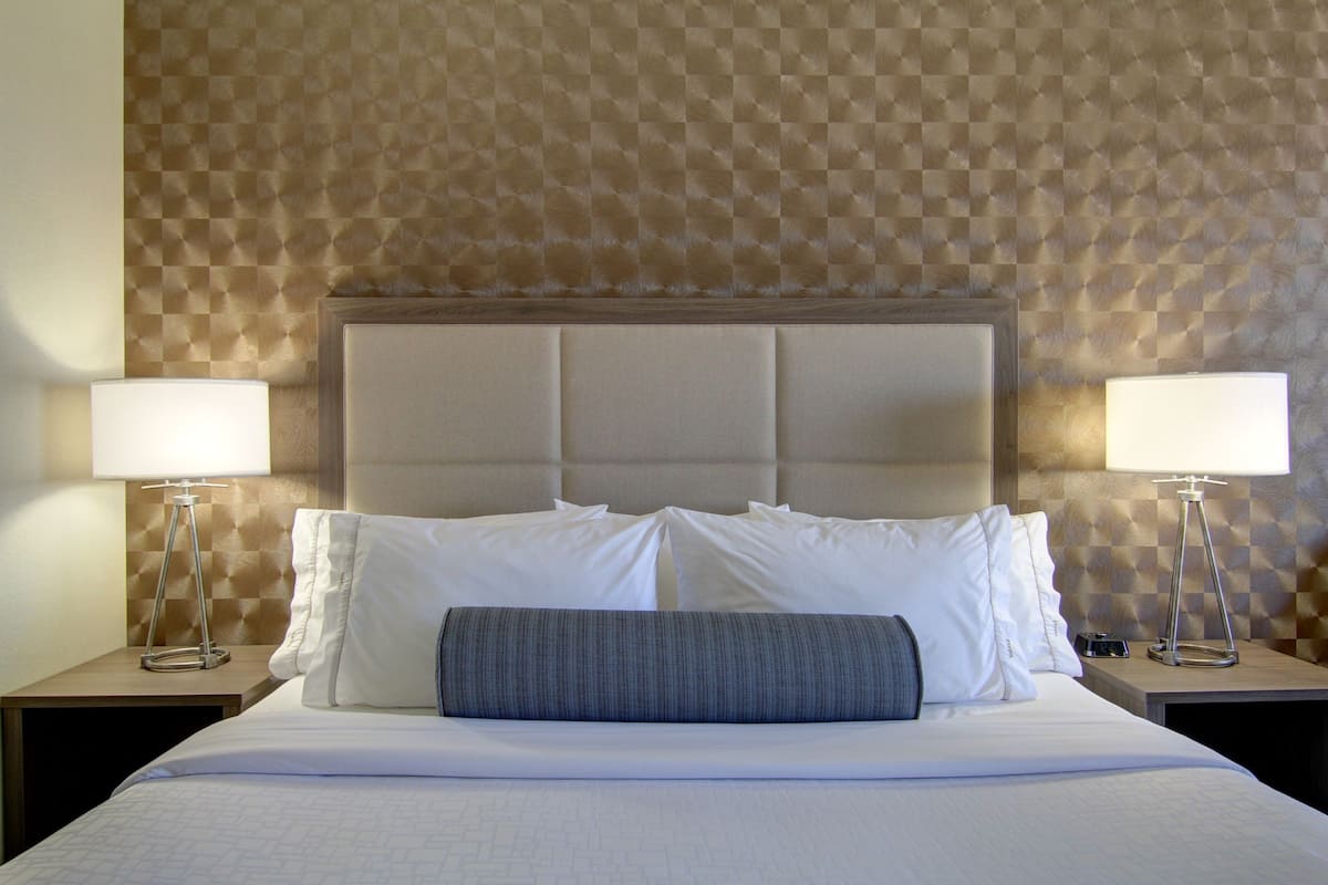 A hotel room with a large bed, two bedside tables, and a checkered wall pattern.