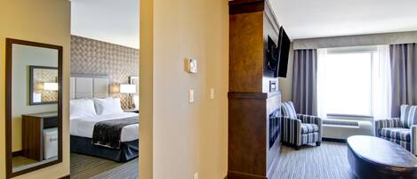 A hotel room with a bed, a desk, a chair, a sofa, and a large window.