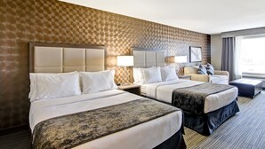 Ett hotellrum med två sängar, en soffa och ett stort fönster.