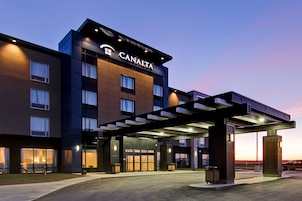 Un hotel CANALTA con una fachada moderna, ventanas amplias y una entrada cubierta.