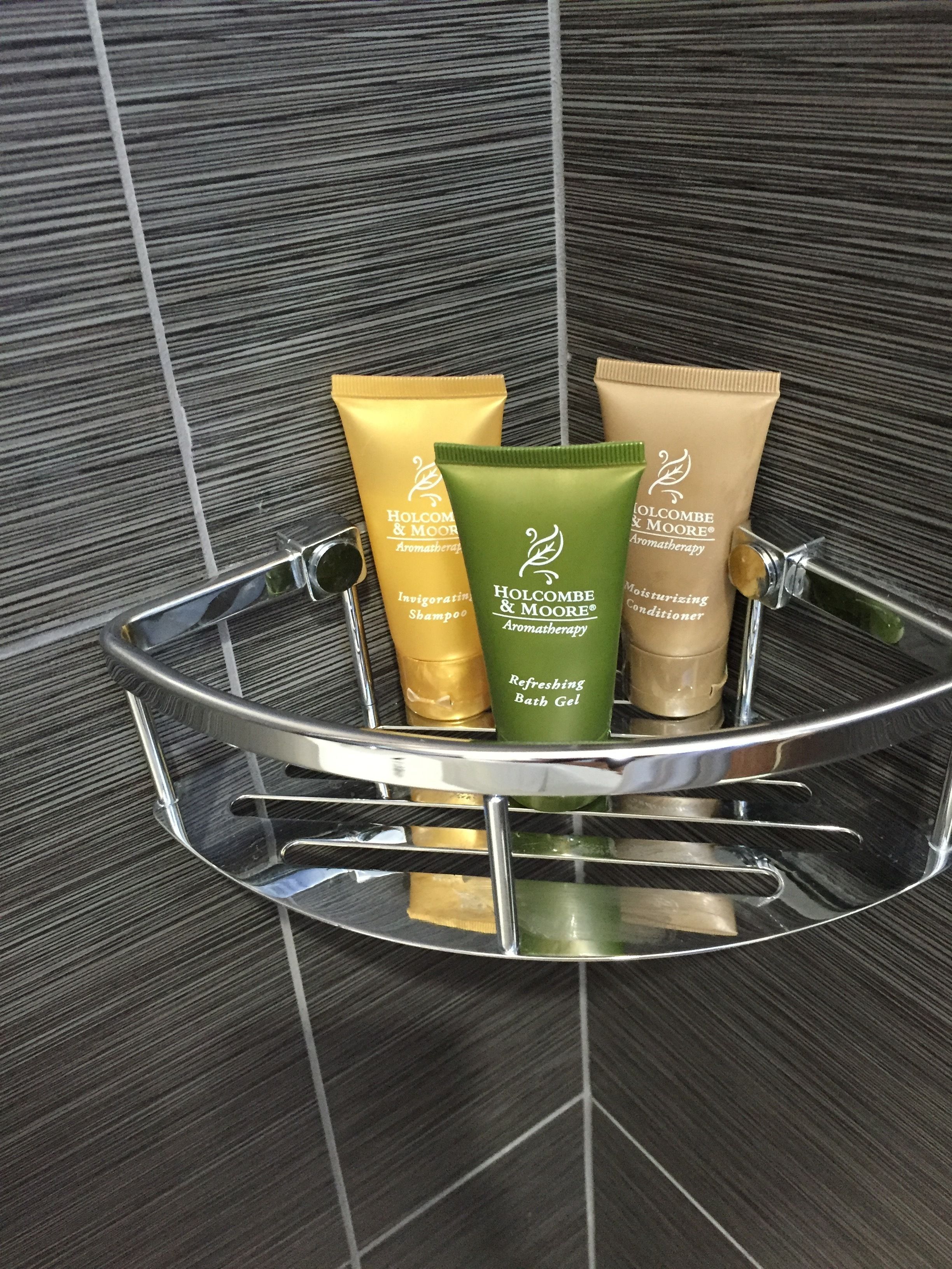 A metal tray holding four toiletries: two tubes of shampoo, one bath gel, and one conditioner.