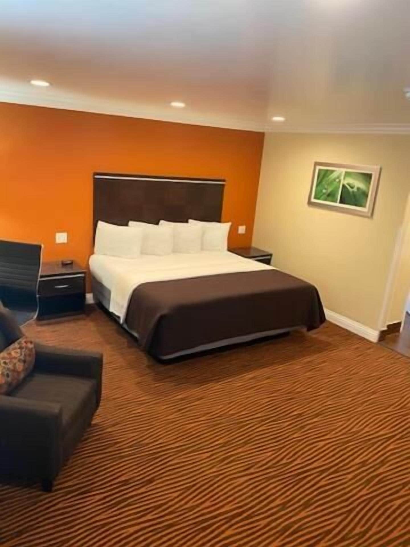 A hotel room with a bed, a nightstand, a chair, and a carpeted floor.