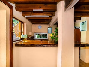 A reception area with a wooden ceiling, a clock, a window, and a plant. - Posada Real del Valle (Valle de Bravo)
