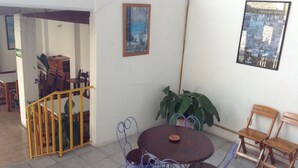 A patio area with a round metal table and chairs, a potted plant, and a staircase leading to an upper level. - Posada Real del Valle (Valle de Bravo)