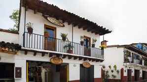 A two-story building with a balcony, potted plants, and a sign indicating it is a family-run establishment. - Posada Valle de Bravo (Valle de Bravo)