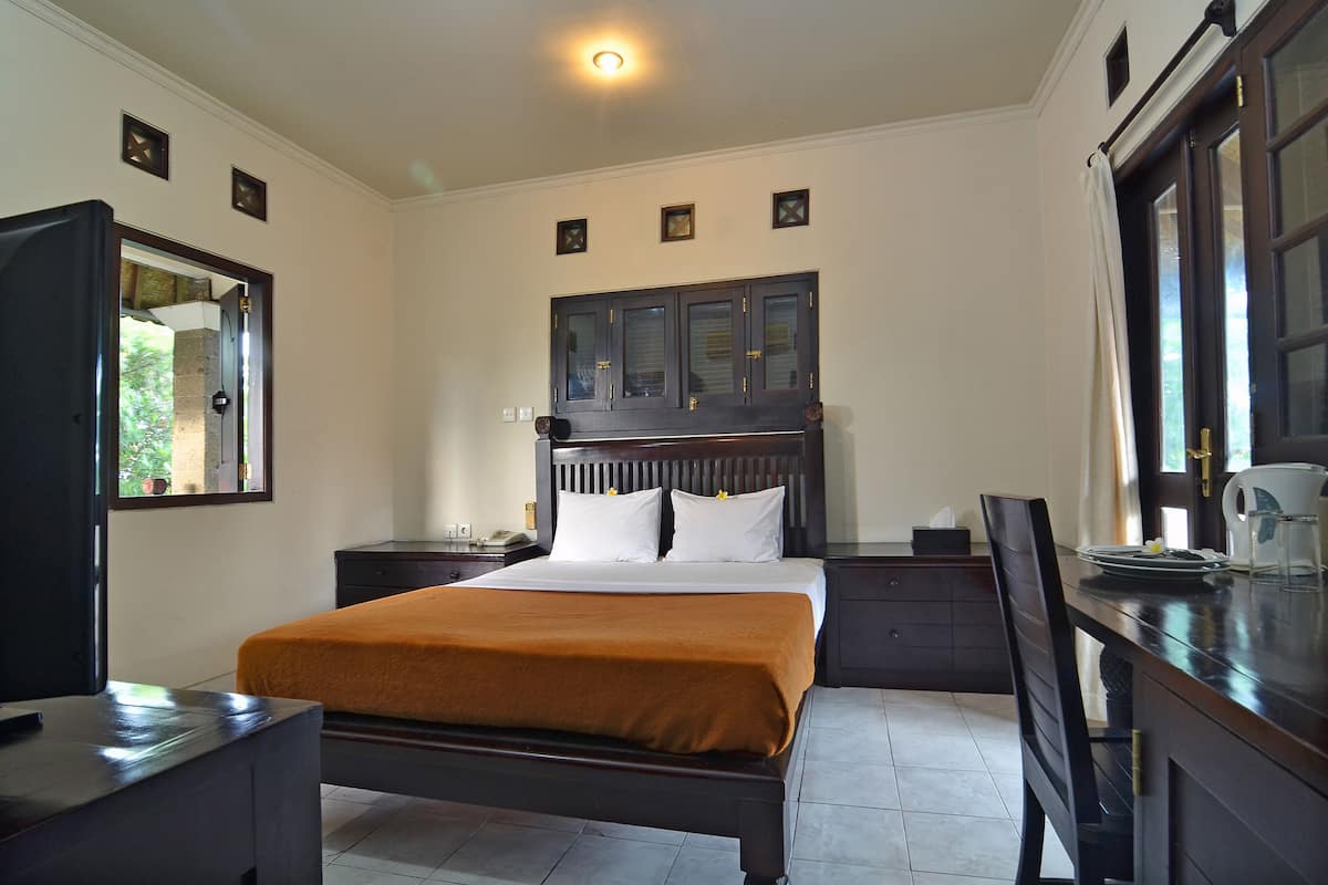 Un dormitorio con cama, escritorio, silla, mesita de noche, armario y ventana.