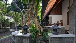 A stone pathway leading to a traditional building with a wooden roof. - Taman Ayu 212 (Denpasar)