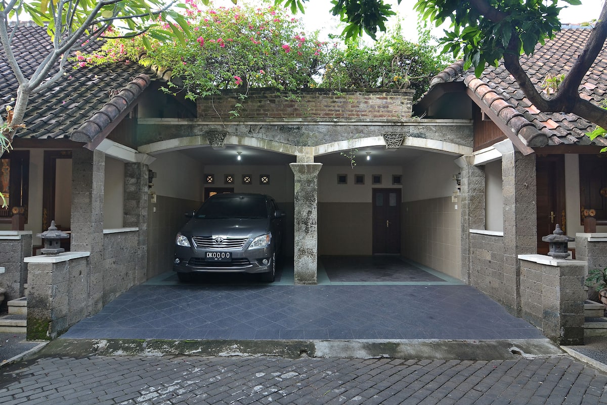 Un coche estacionado en un área de aparcamiento cubierto, con fachada de piedra y techo de tejas.
