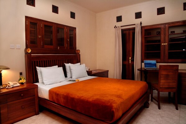 Une chambre d’hôtel avec un lit en bois, un bureau avec un ordinateur portable et une chaise.