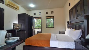 A bedroom with a bed, a nightstand, a dresser, and a window with a view of greenery. - Taman Ayu 212 (Denpasar)