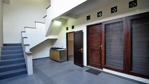 A staircase leading to a second floor, a closed wooden door, and a closed shuttered door. - Taman Ayu 212 (Denpasar)